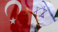A demonstrator burns an Israeli flag